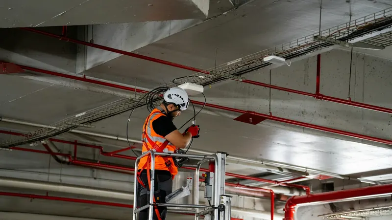 Construction worker on lift installing ceiling components — stock photo
