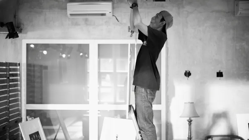 Electrician works on wiring from a ladder indoors — stock photo